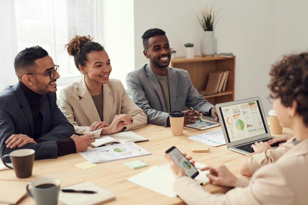 Young professionals discussing work at a conference table with technology and documents.